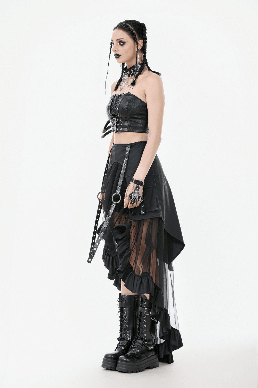 Gothic woman in layered mesh high-low ruffle skirt, strapped top, and chunky boots, showcasing punk style.