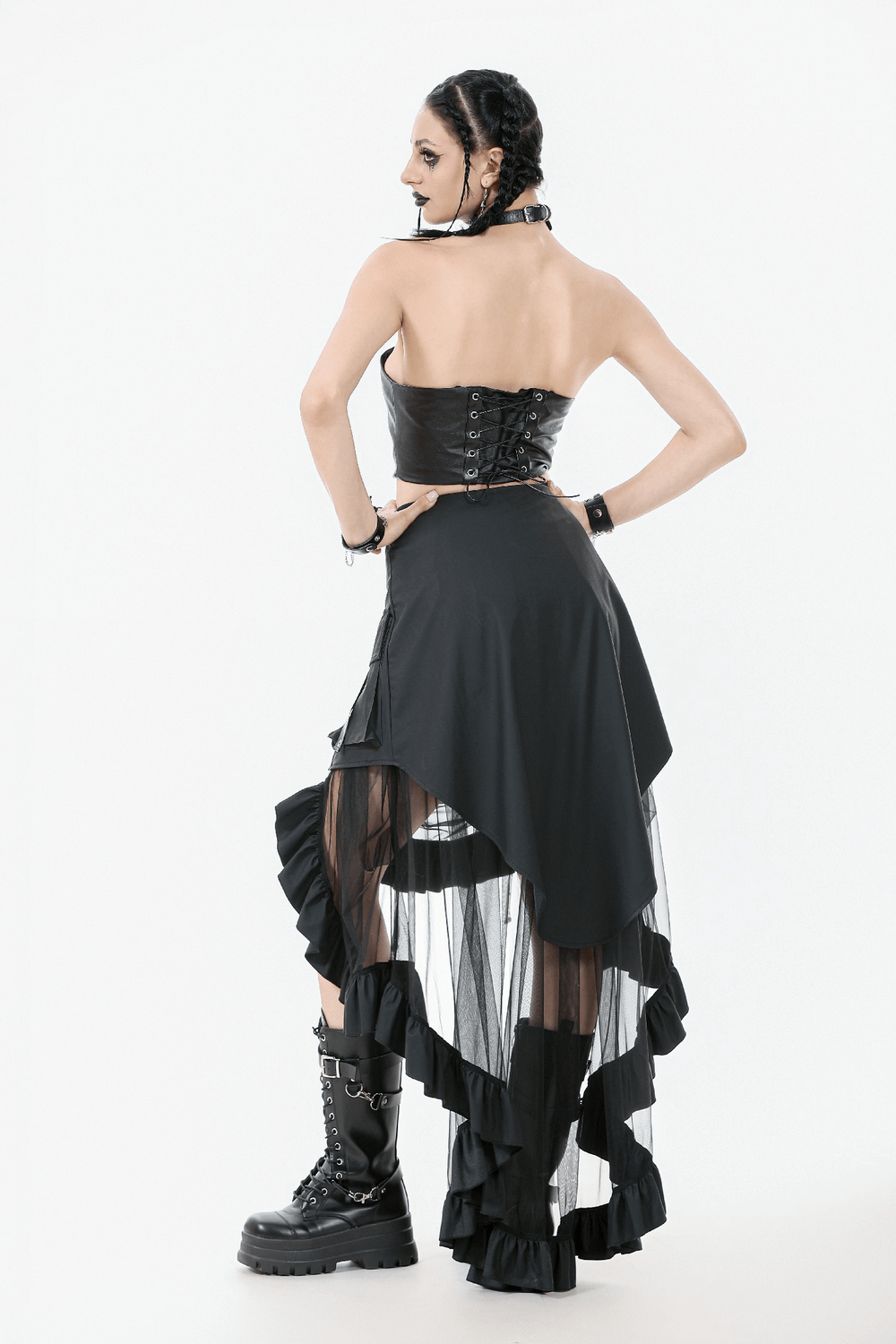 Back view of a woman in a black asymmetrical ruffle skirt and corset, showcasing a punk gothic fashion style.