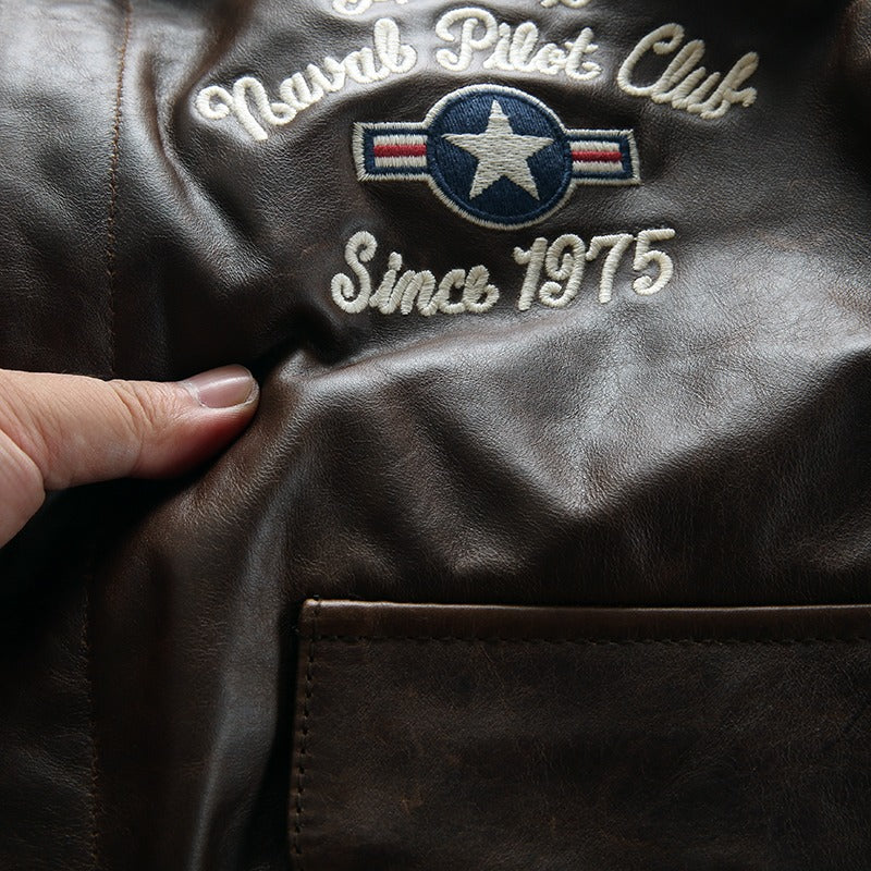 Close-up of brown leather jacket with embroidered Naval Pilot Club logo and patches, showcasing quality craftsmanship.