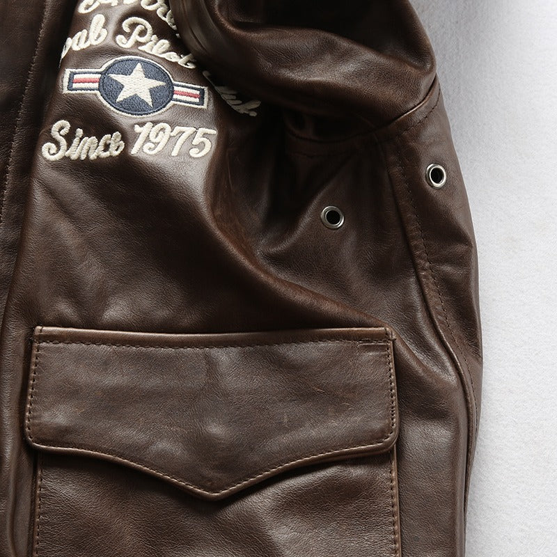 Close-up of a brown leather biker jacket featuring embroidered patches and a stylish pocket.