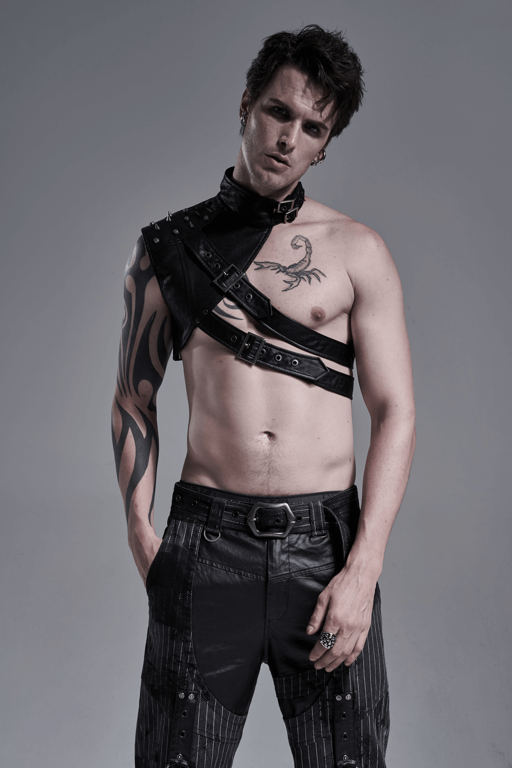 Punk men's leather shoulder harness showcasing edgy one-arm armor with bold metal rivets and striking tattoo.