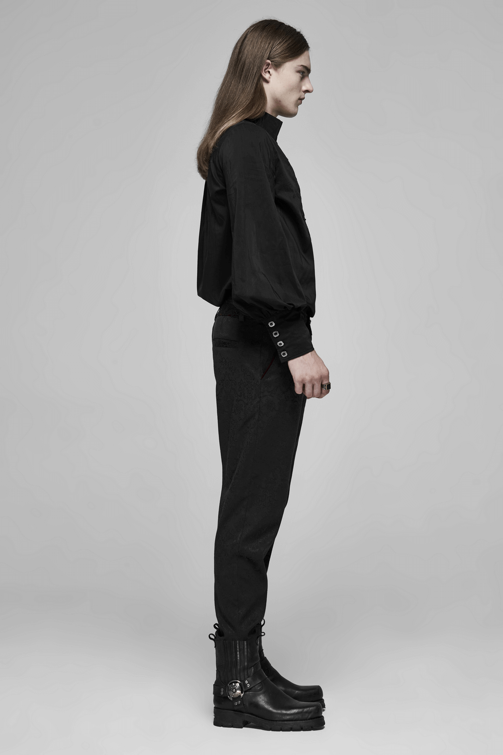 Gothic fashion model in black long sleeve shirt and pants, showcasing a stylish side profile with unique boots.