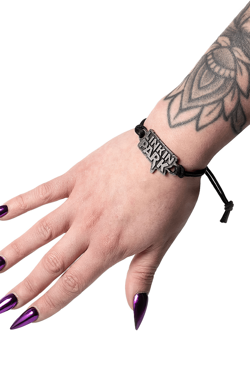 Linkin Park pewter logo bracelet on a hand with tattoos and purple nails, featuring an adjustable black cord strap.