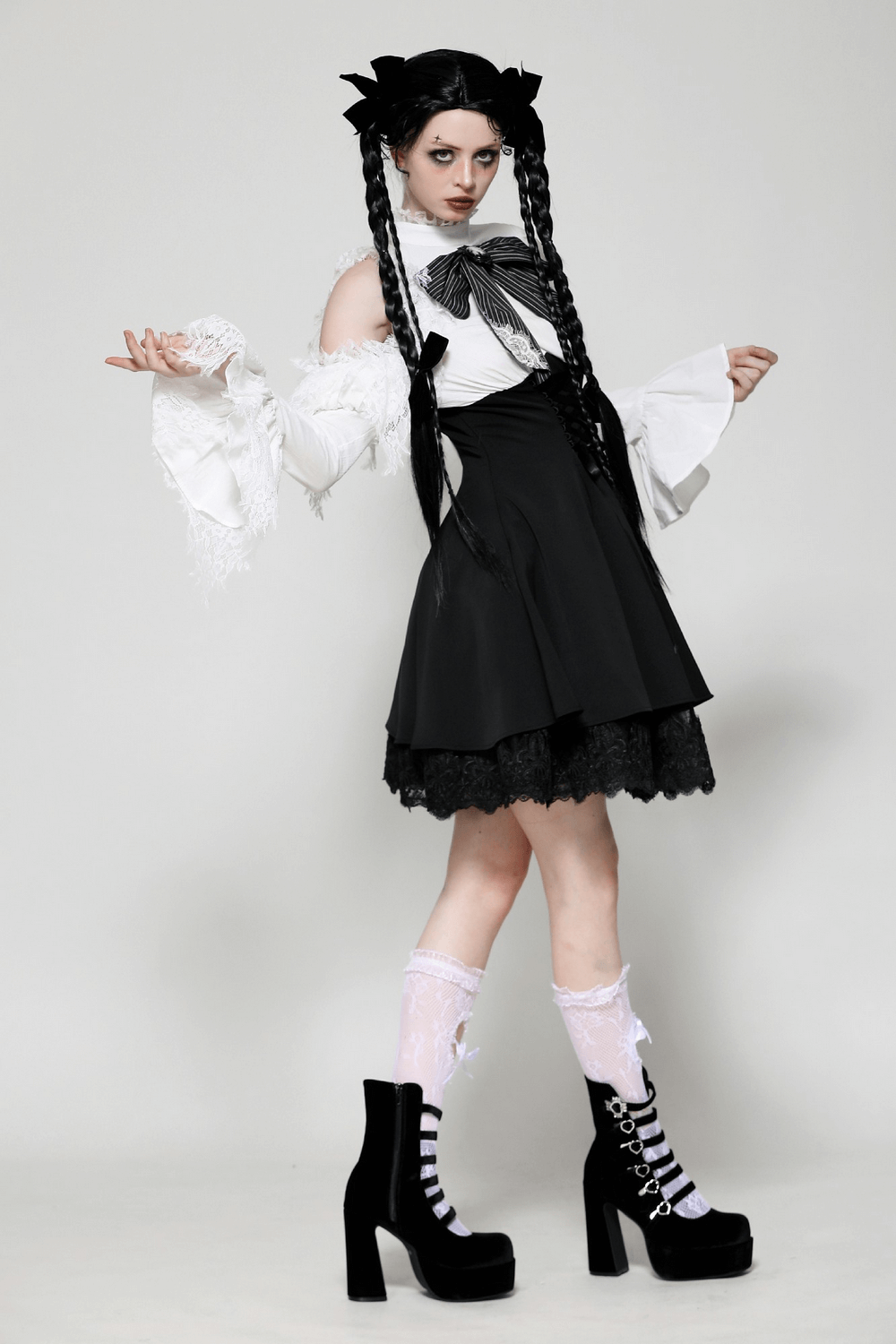 Stylish model wearing a black and white Lolita dress with lace sleeves and platform boots, showcasing gothic elegance.