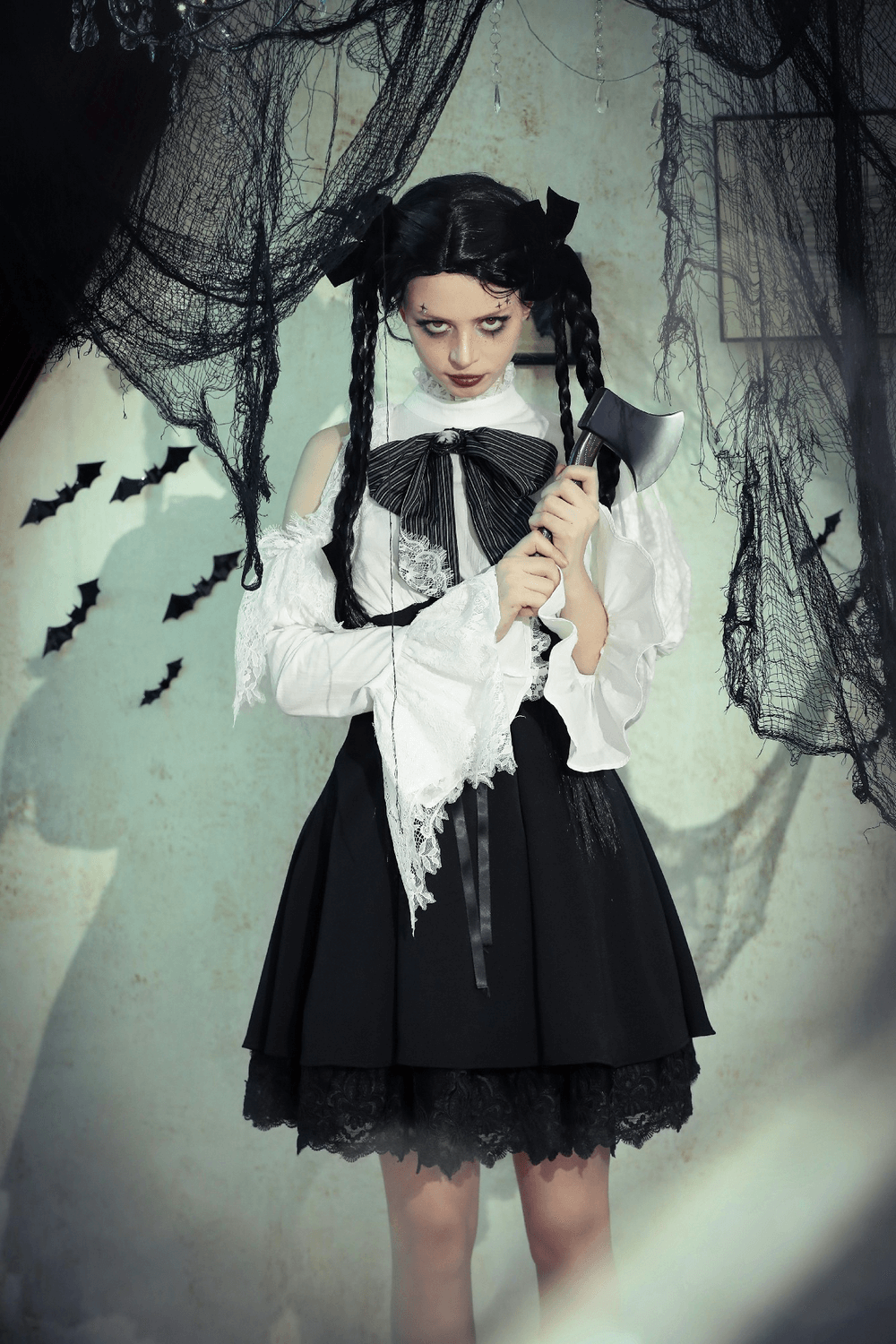 Gothic-inspired model in black and white outfit with ribbon bow and lace accents, set against a spooky backdrop.