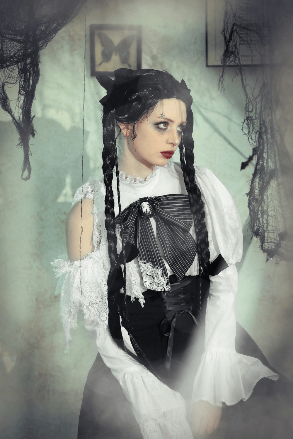 Elegant woman in a black and white gothic Lolita dress with lace sleeves and a corset waist, set in a moody, atmospheric background.