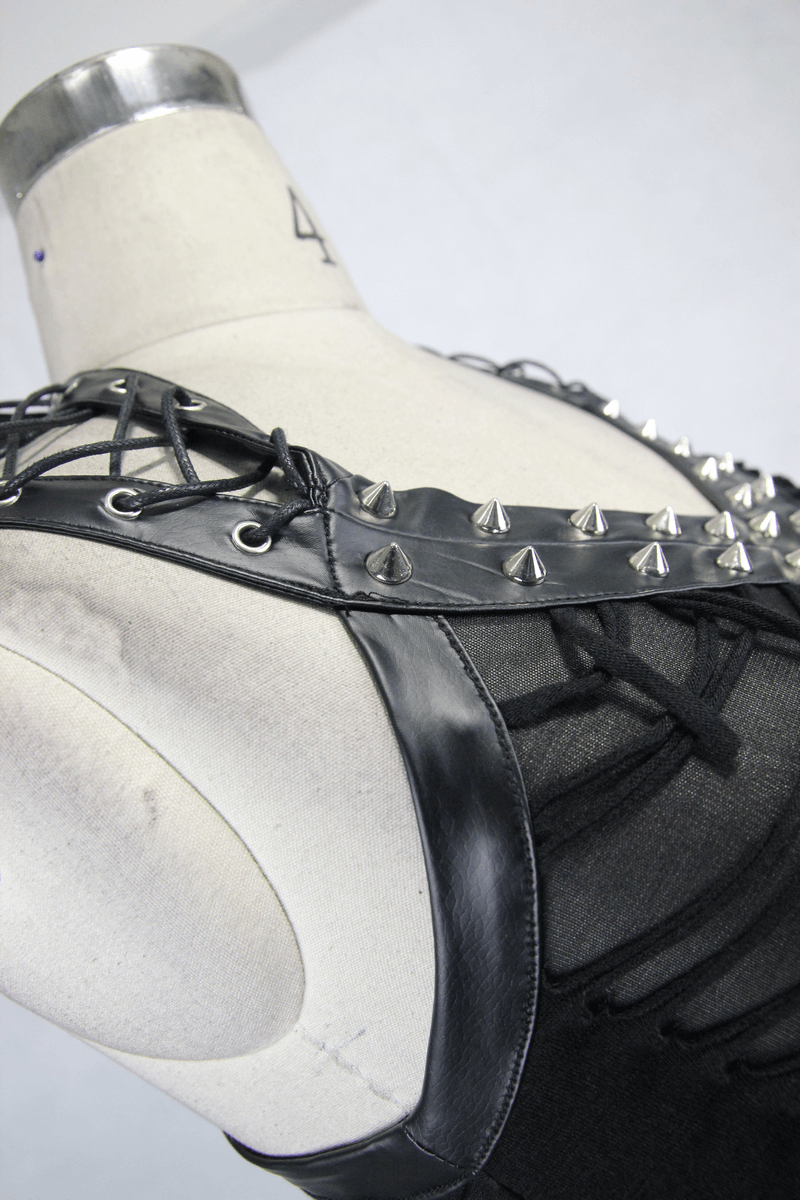 Close-up of a black punk top with lace-up leatherette straps and silver metal spikes.
