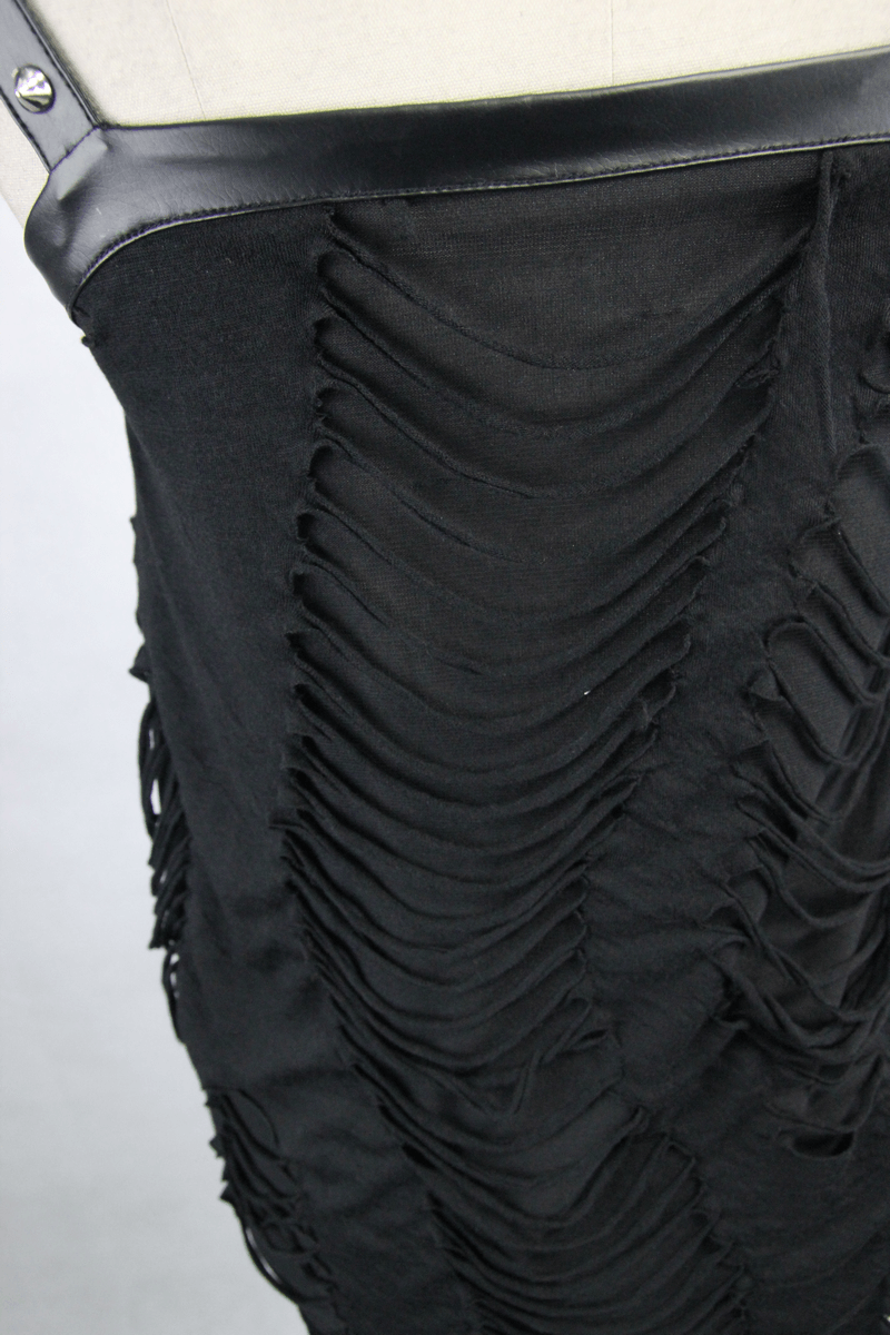 Close-up of a women's black top with a ripped effect and leatherette straps in punk style.