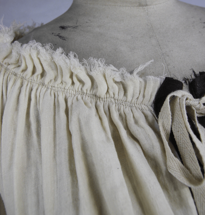 Close-up of beige vintage blouse featuring off-shoulder design and lacing detail at the neckline.