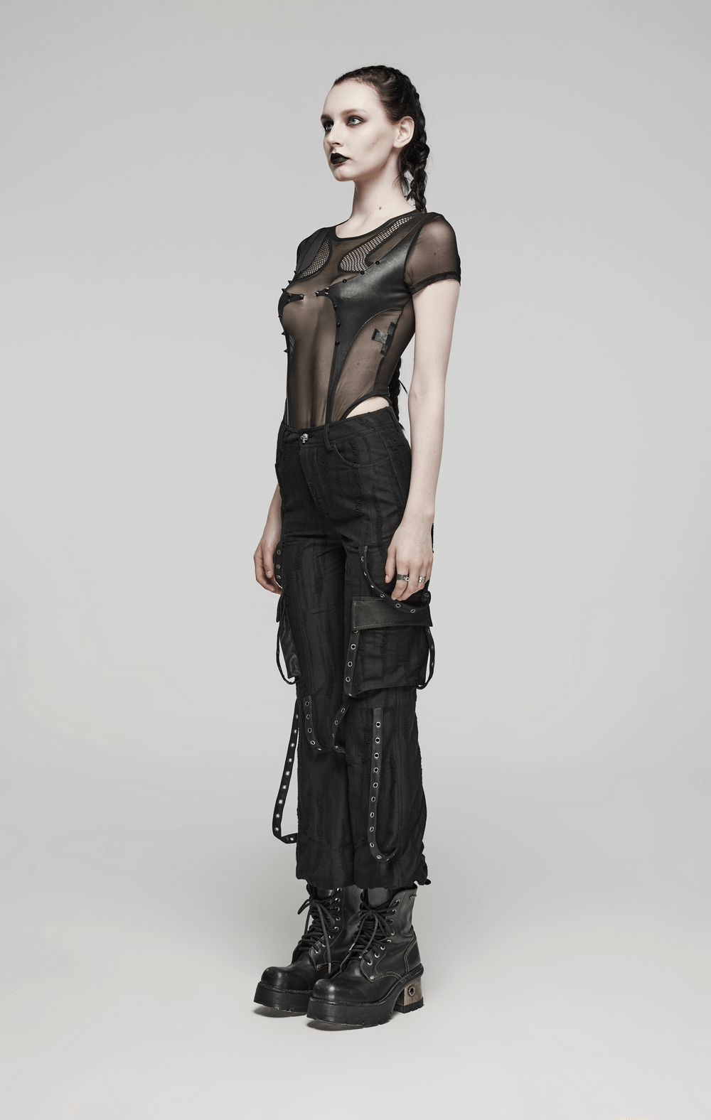Model wearing loose-fit black gothic streetwear cargo pants and sheer top with edgy styling and accessories.