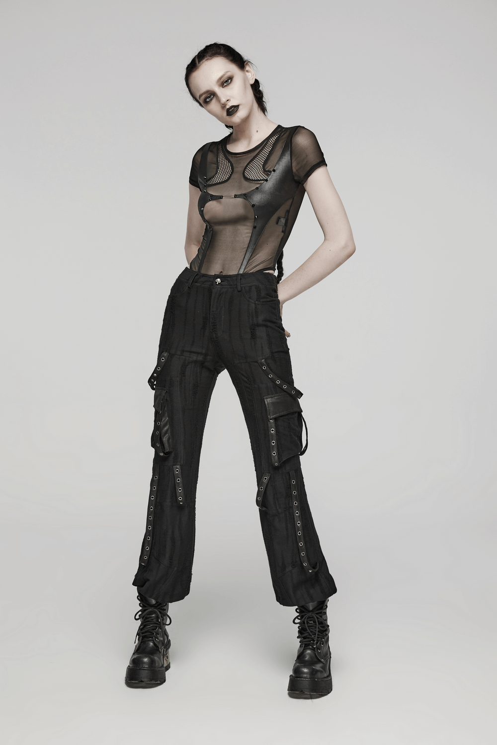 Model showcasing loose-fit black gothic streetwear cargo pants with a sheer top and combat boots.