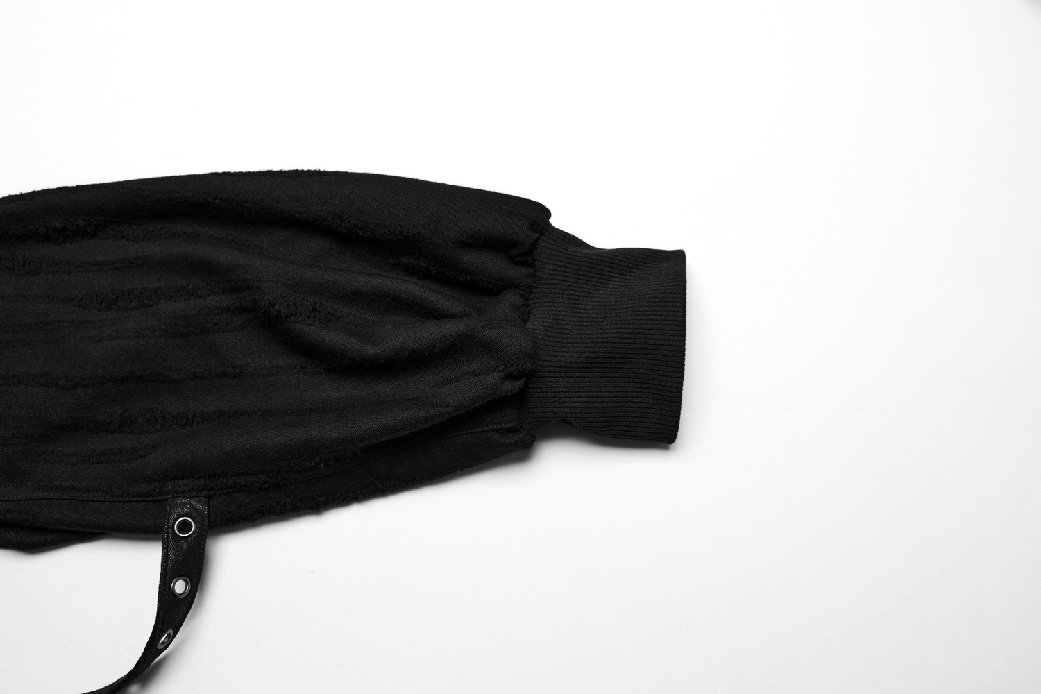 Close-up of a loose-fit black gothic cargo pant sleeve with textured fabric and stylish o-ring detail.