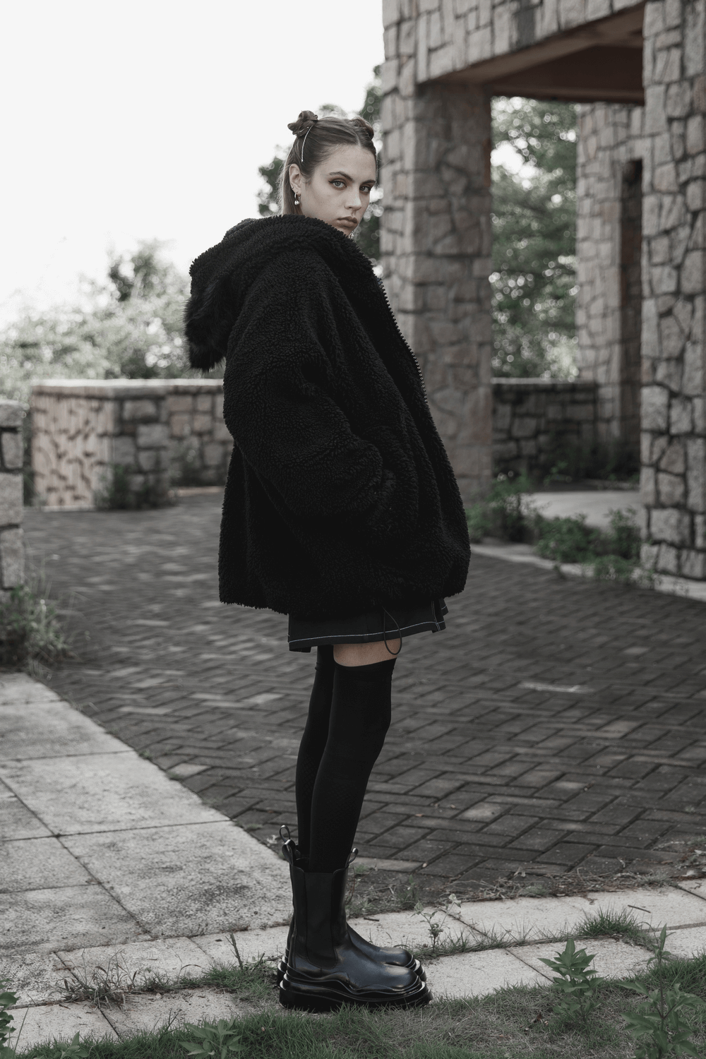 Stylish woman in a fluffy black fox ear hooded jacket, showcasing a loose fit and cool aesthetic.