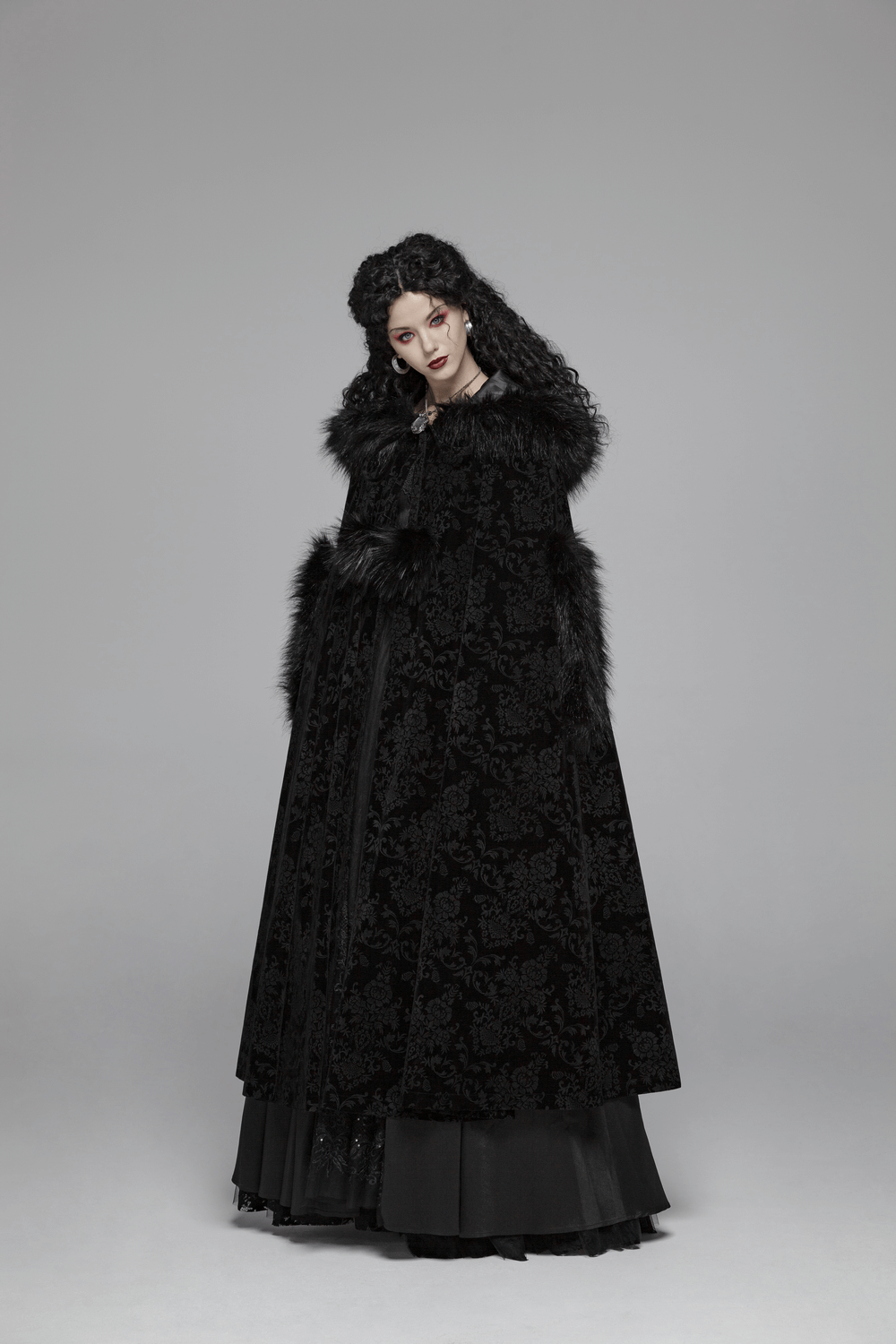 Elegant lady in a black velvet hooded Gothic cloak with fur trim, showcasing a dramatic full-length design.