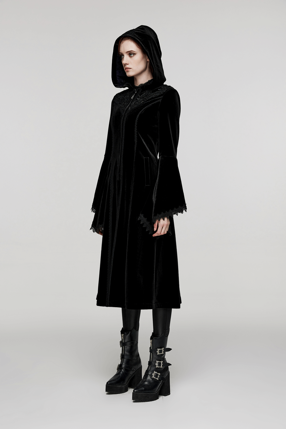 Elegant woman in a luxurious hooded velvet coat with gothic flair and bell sleeves, perfect for winter.