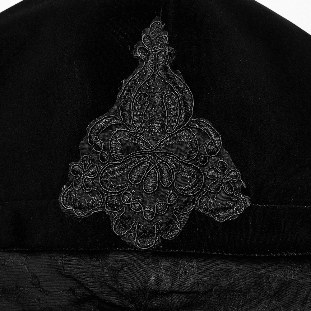 Intricate black embroidery detail on the hood of a luxurious gothic velvet coat.