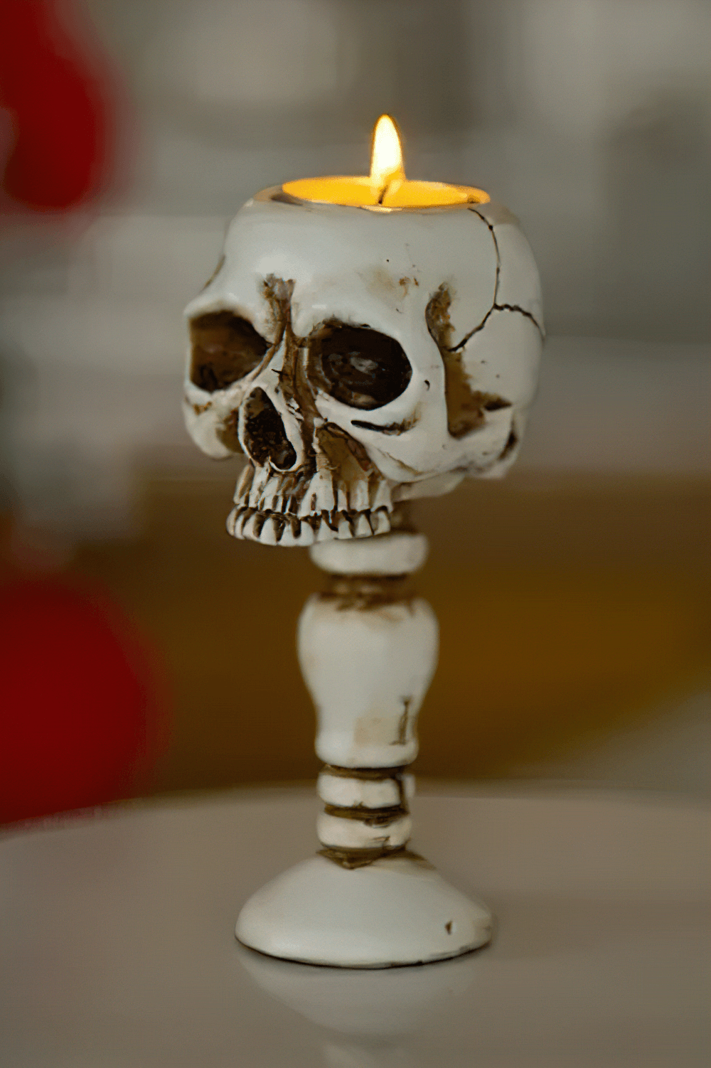 Macabre Skeleton Candle Stand for Haunted Decor with glowing candle atop skull holder.