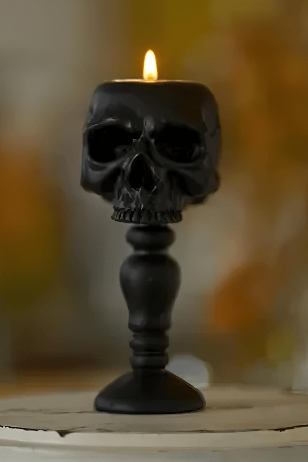 Macabre Skeleton Candle Stand for Haunted Decor with black skull design and candle flame.
