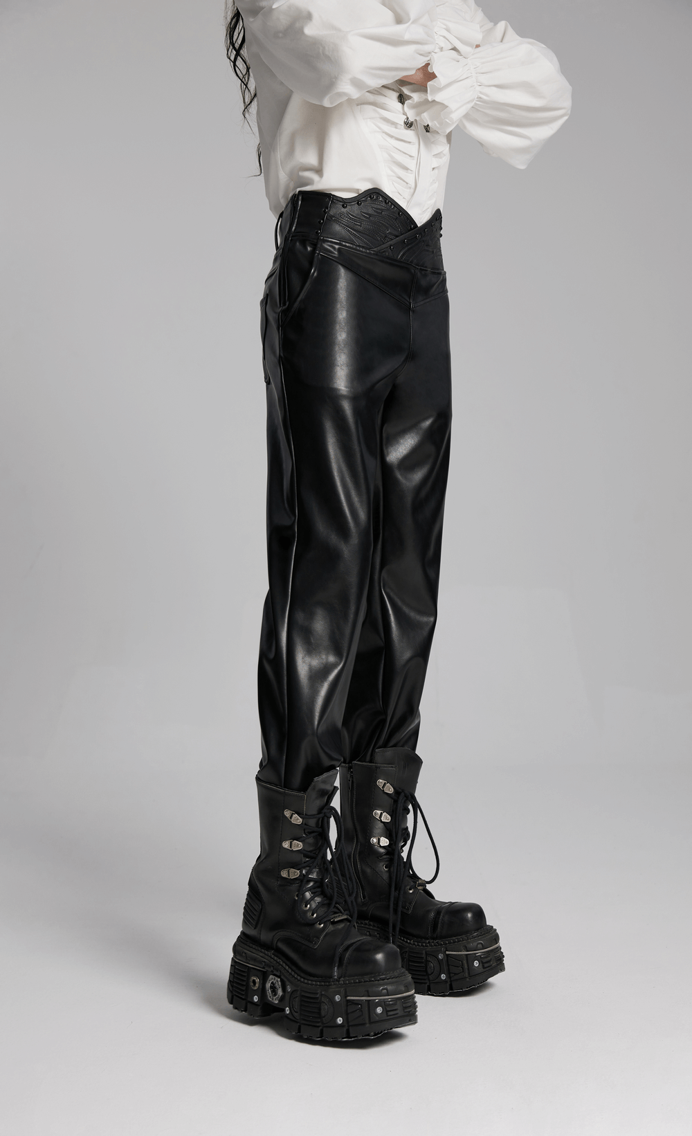 Male model wearing punk minimalist faux leather pants with unique 3D curved waistband and chunky combat boots.