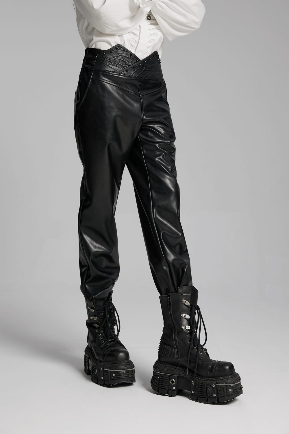 Black male faux leather pants with 3D curved waistband and studded details, styled with chunky platform boots.