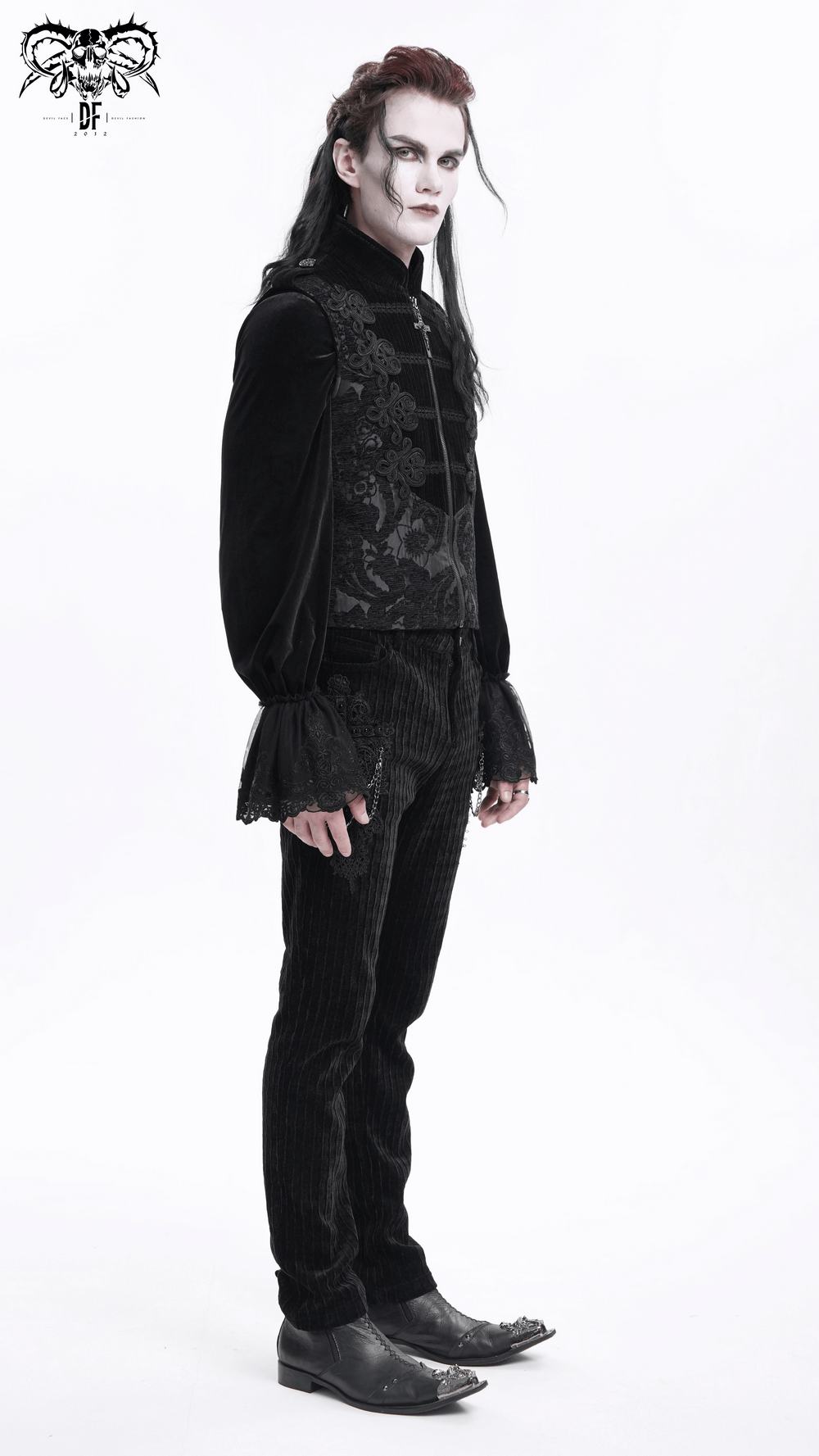 Male model in gothic black brocade waistcoat, featuring intricate embroidery, standing elegantly in a minimalist setting.