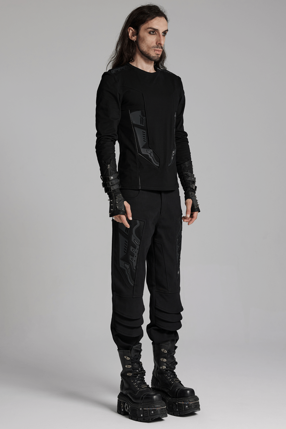 Male model in black cyberpunk outfit with 3D armor patches, showcasing stylish elastic twill pants and edgy boots.