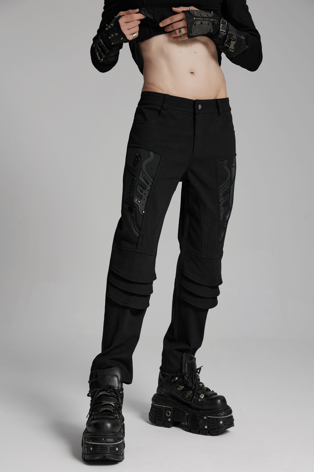 Male model showcasing black cyberpunk pants with 3D armor patches and stylish black boots.