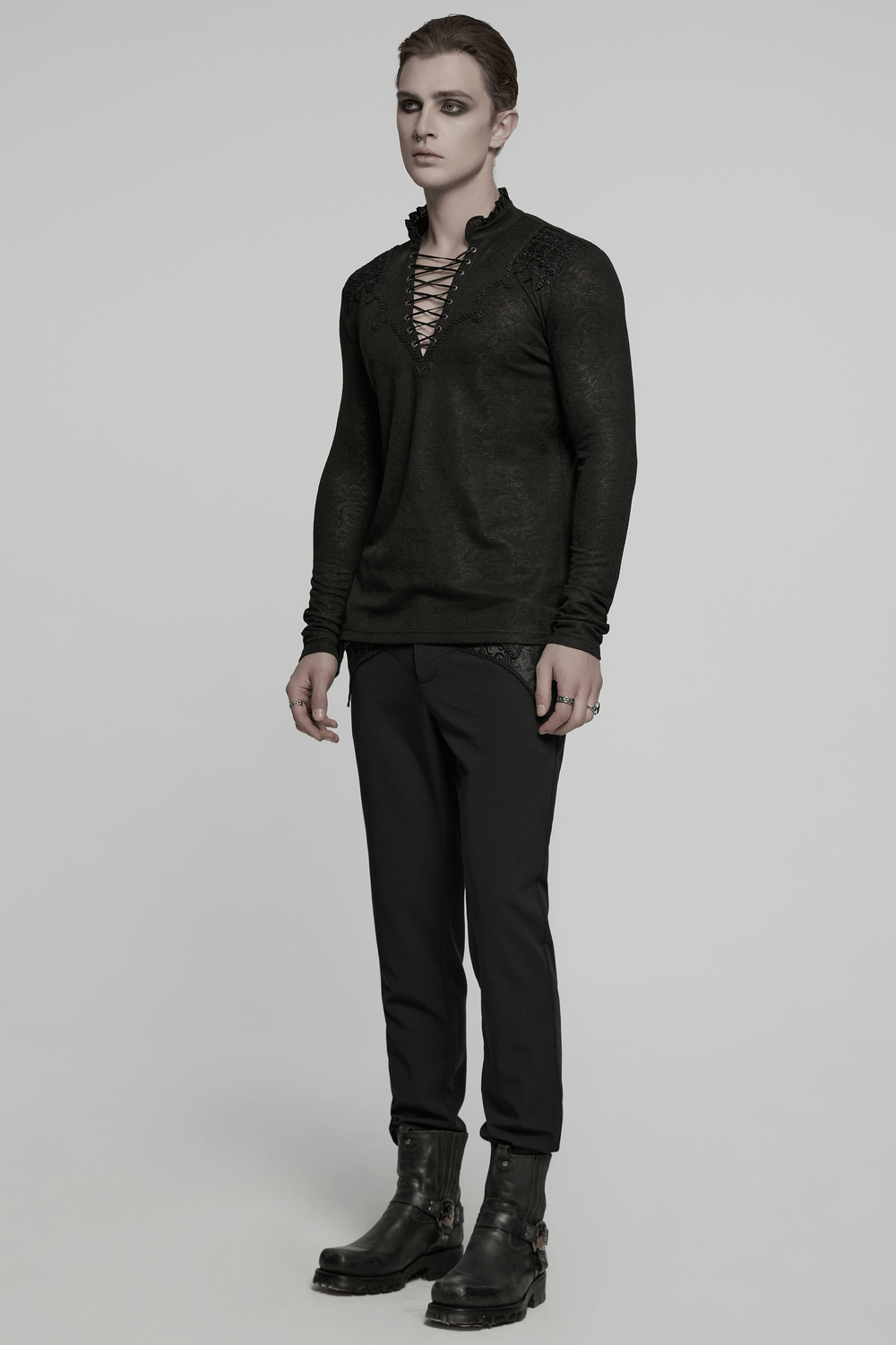 Male model wearing a black lace-up gothic top with ruffled collar, paired with dark pants and boots.