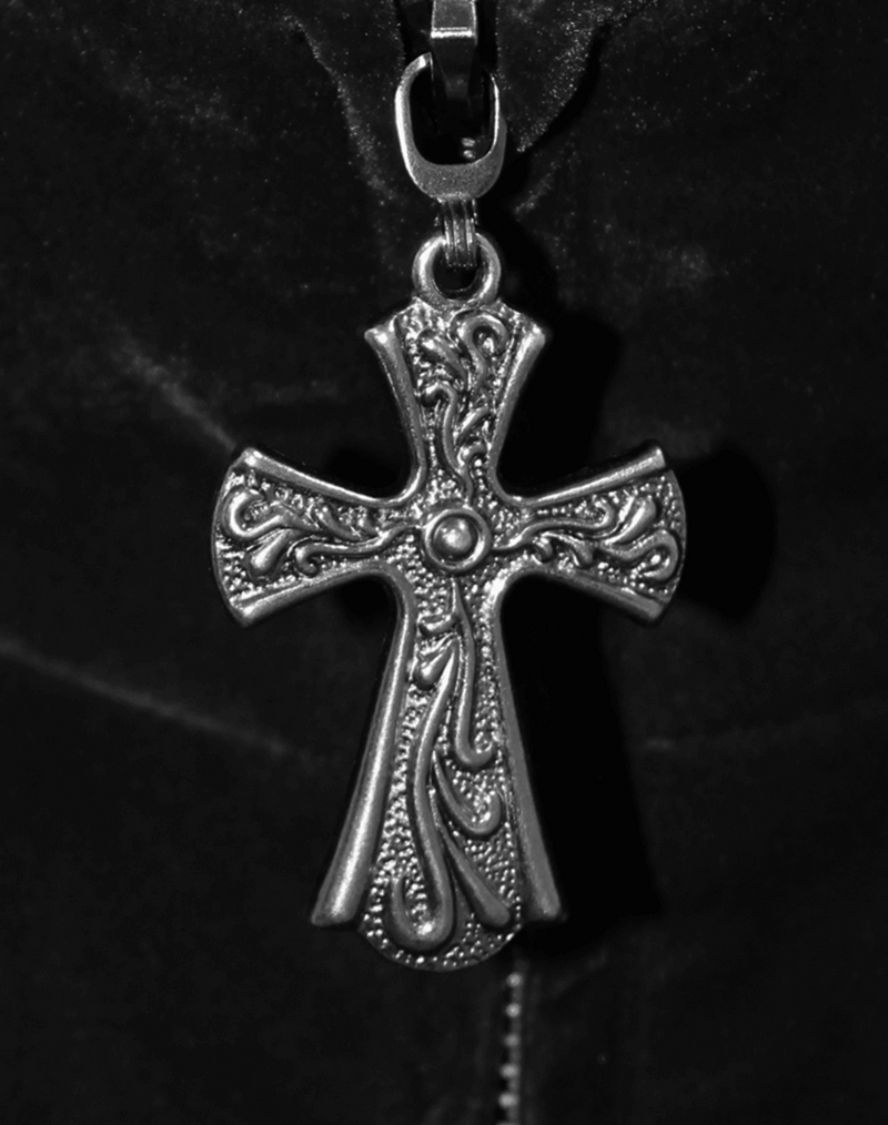 Close-up of an intricately designed silver cross necklace pendant, perfect for gothic fashion.
