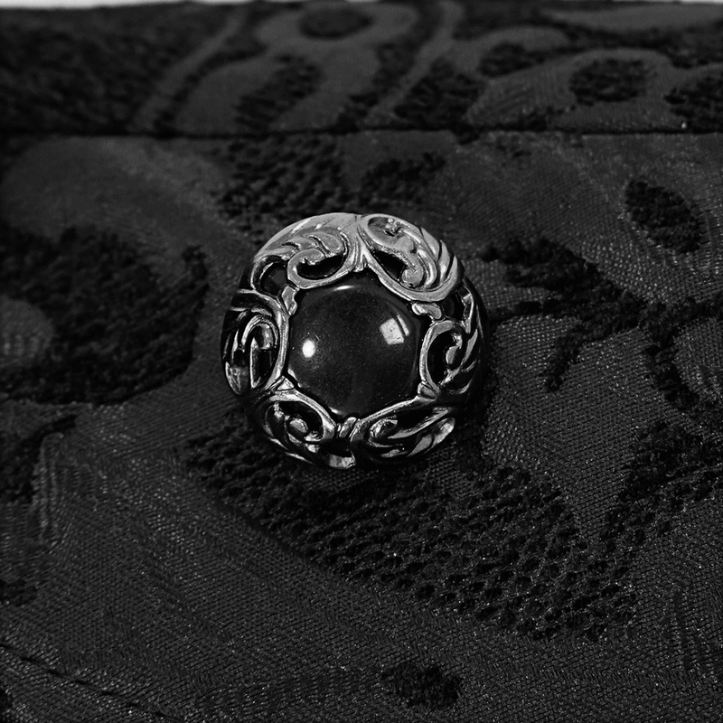 Close-up of an ornate black button with silver filigree on gothic fabric, perfect for adding elegance to a cloak.