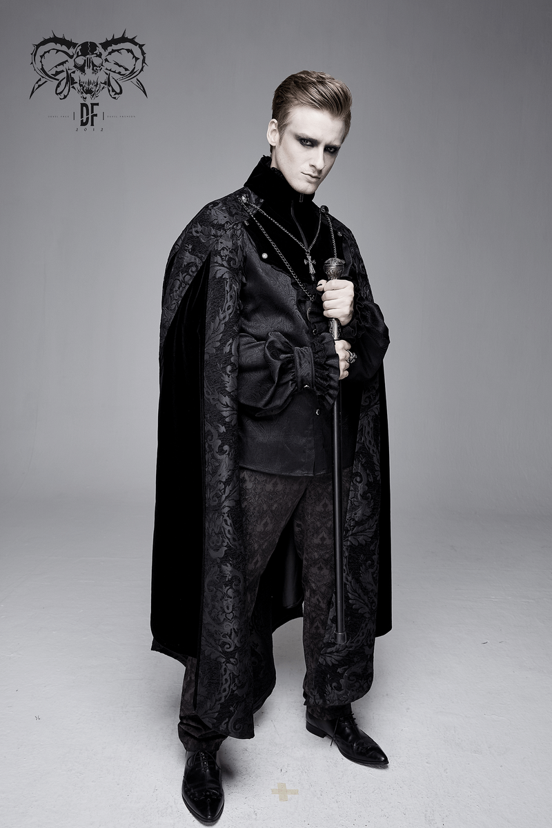 Elegant male model in a black gothic cloak with stand-up collar, stylishly posing with a cane.