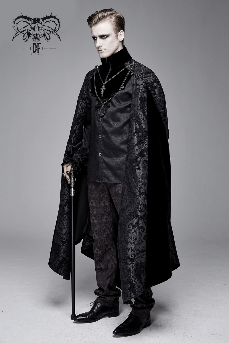 Elegant male model in a gothic black long cloak with stand-up collar and medallion necklace, showcasing a stylish gothic look.