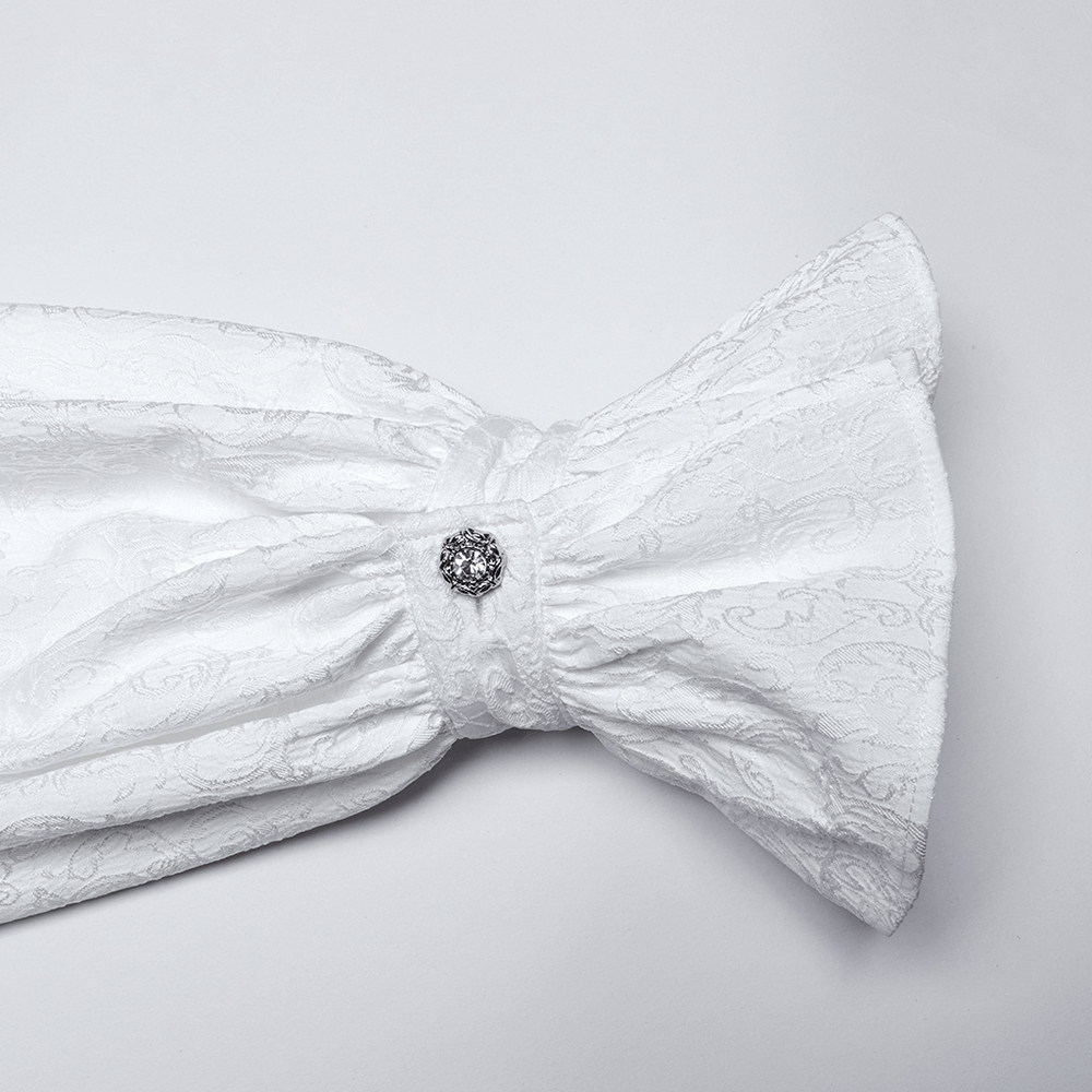 Close-up of a luxurious white fabric with a decorative button, showcasing intricate patterns and elegant textures.