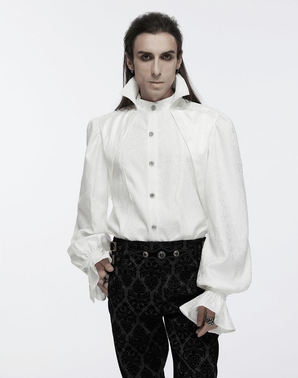 Male model in a white gothic stand collar shirt with bubble sleeves, paired with black patterned pants, showcasing elegance.