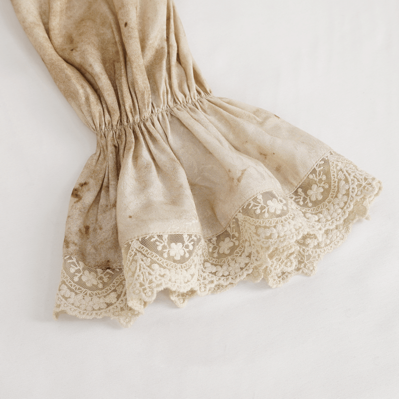 Detail of a vintage-style lantern sleeve with lace trim in soft beige, showcasing its distressed texture.
