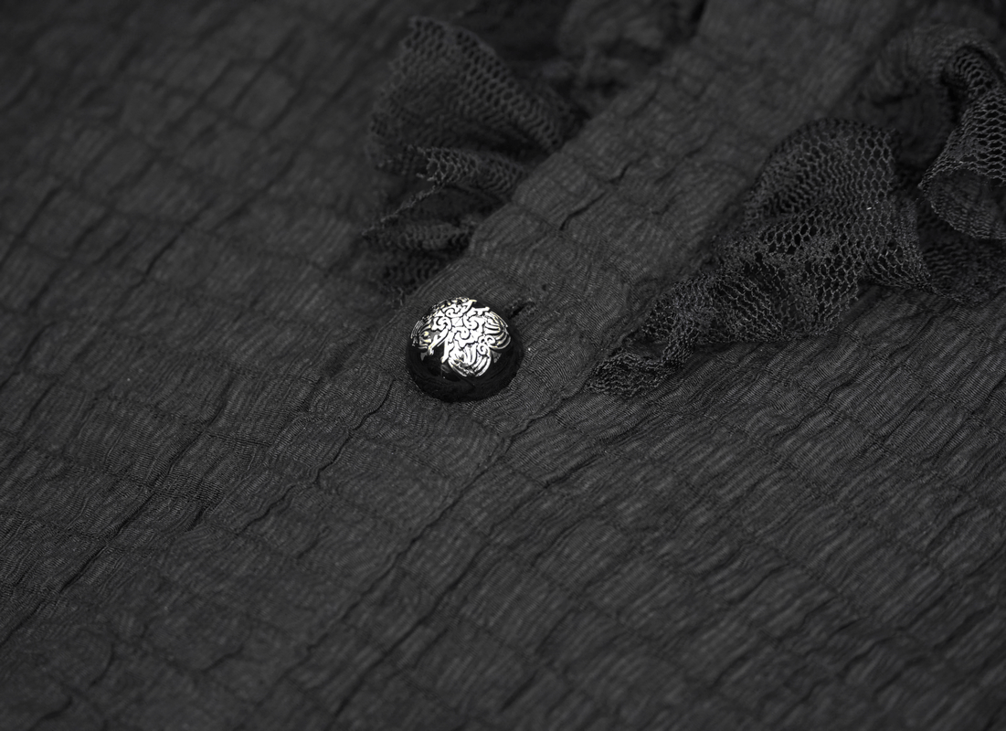Close-up of a black gothic vintage shirt featuring ruffles and an ornate button detail.