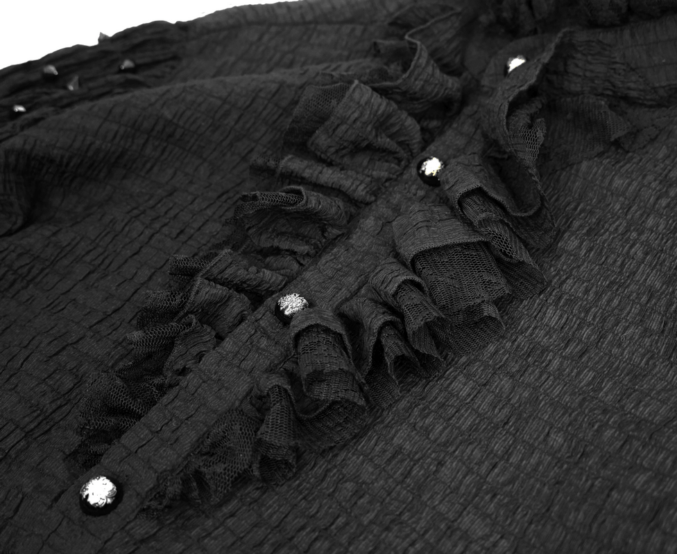 Close-up of vintage black gothic men's shirt featuring ruffles and shiny buttons, showcasing elegant fabric texture.