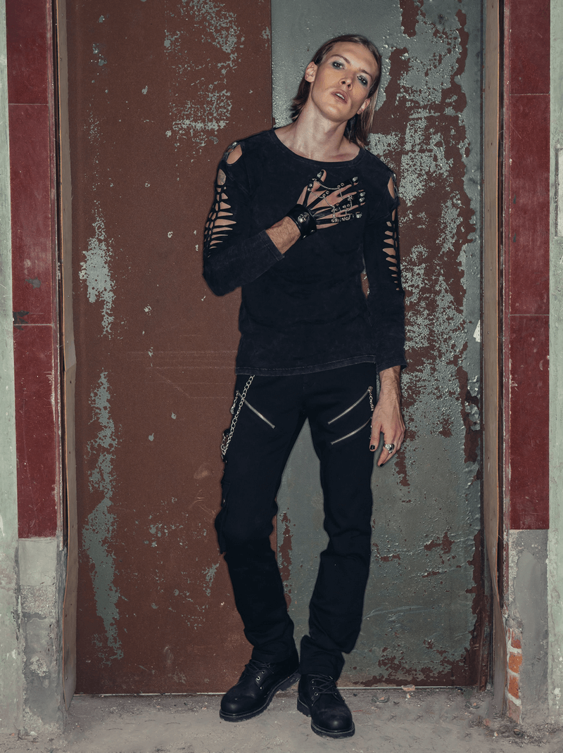 Stylish male model in punk rock outfit with black ripped sweater and pants featuring zipper details and chains.