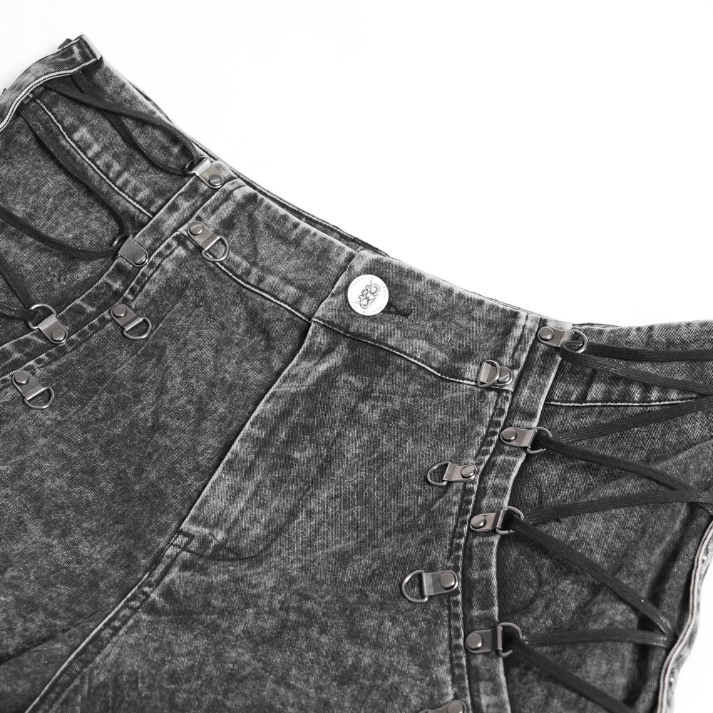 Close-up of male ripped legs pants with lace-up sides and metal buckle details in faded black denim.