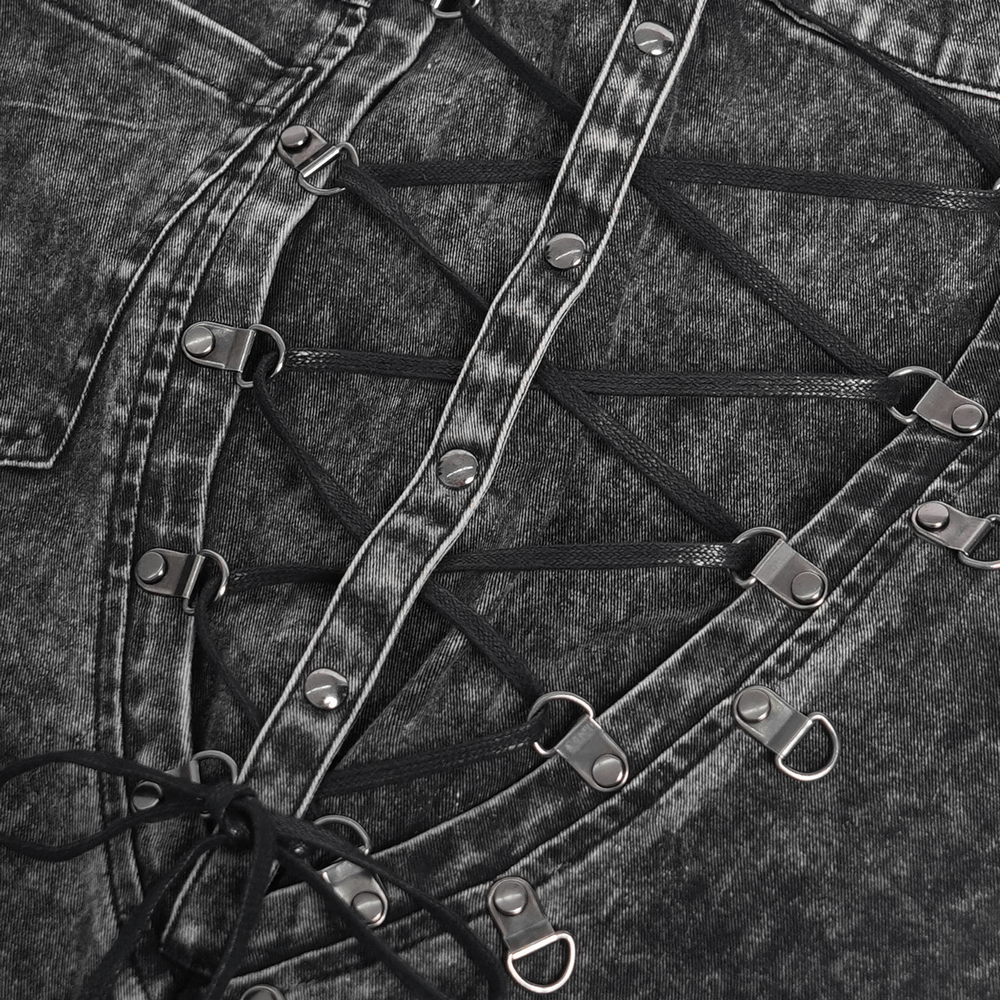 Close-up of gothic ripped pants showing lace-up details and metal studs on washed black denim.