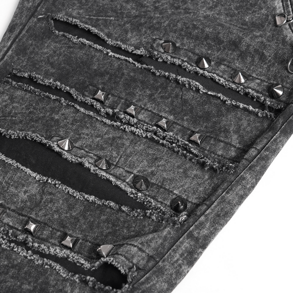 Close-up of ripped black denim pants featuring studded details and distressed edges for a grunge gothic style.