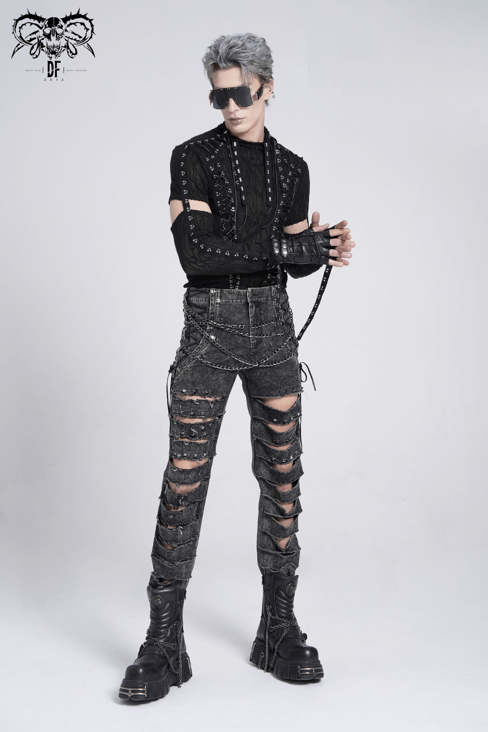 Male model in ripped grunge pants with chains and studs, showcasing a bold gothic style and edgy fashion vibes.