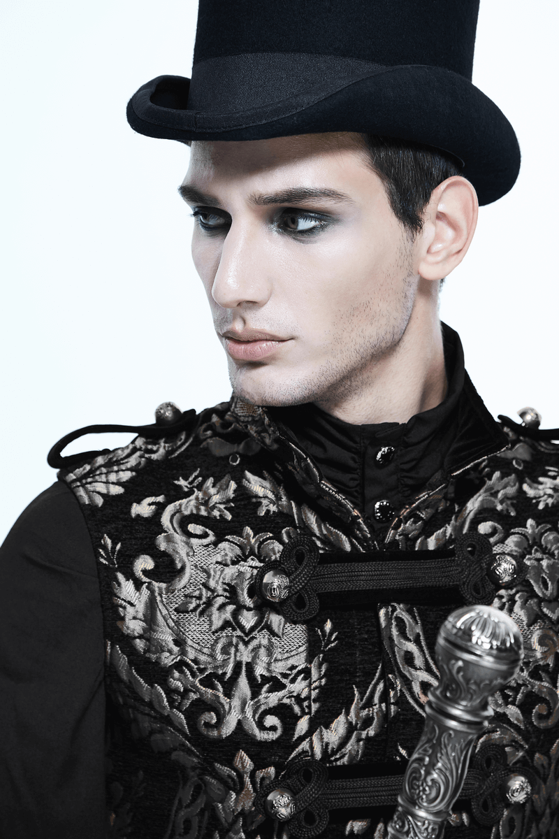 Stylish man in a gothic sleeveless coat with silver embroidery and a black top hat, showcasing vintage elegance.