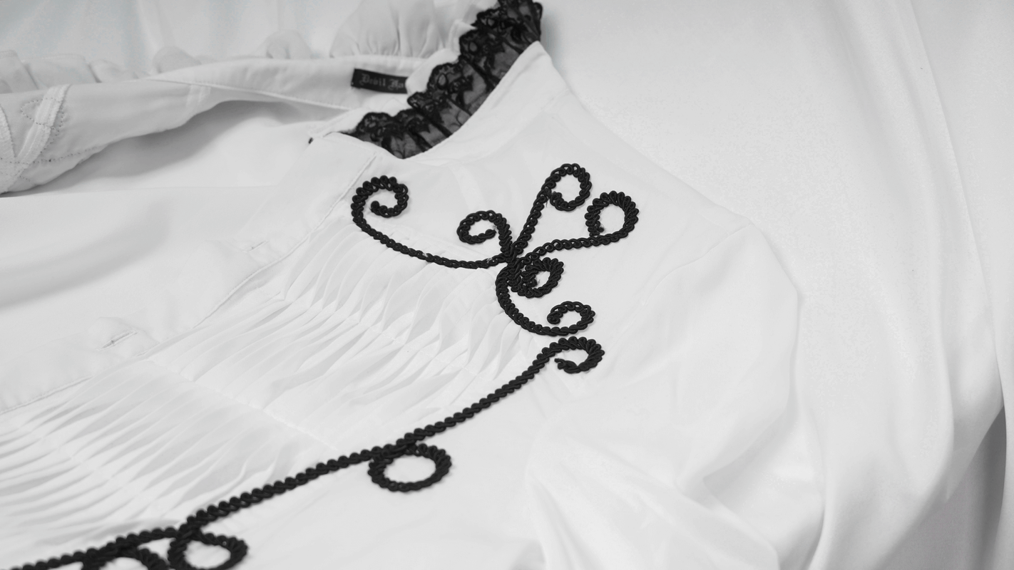 Close-up of a vintage white gothic shirt showcasing lace detailing on the collar and decorative patterns.