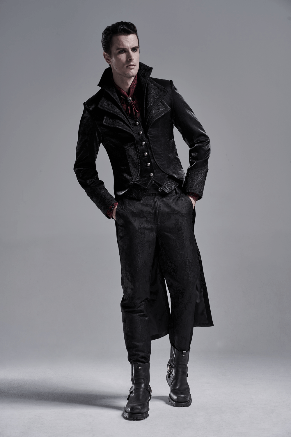 Male model in a stylish black gothic outfit with a red scarf, exuding a dramatic, vampiric vibe.