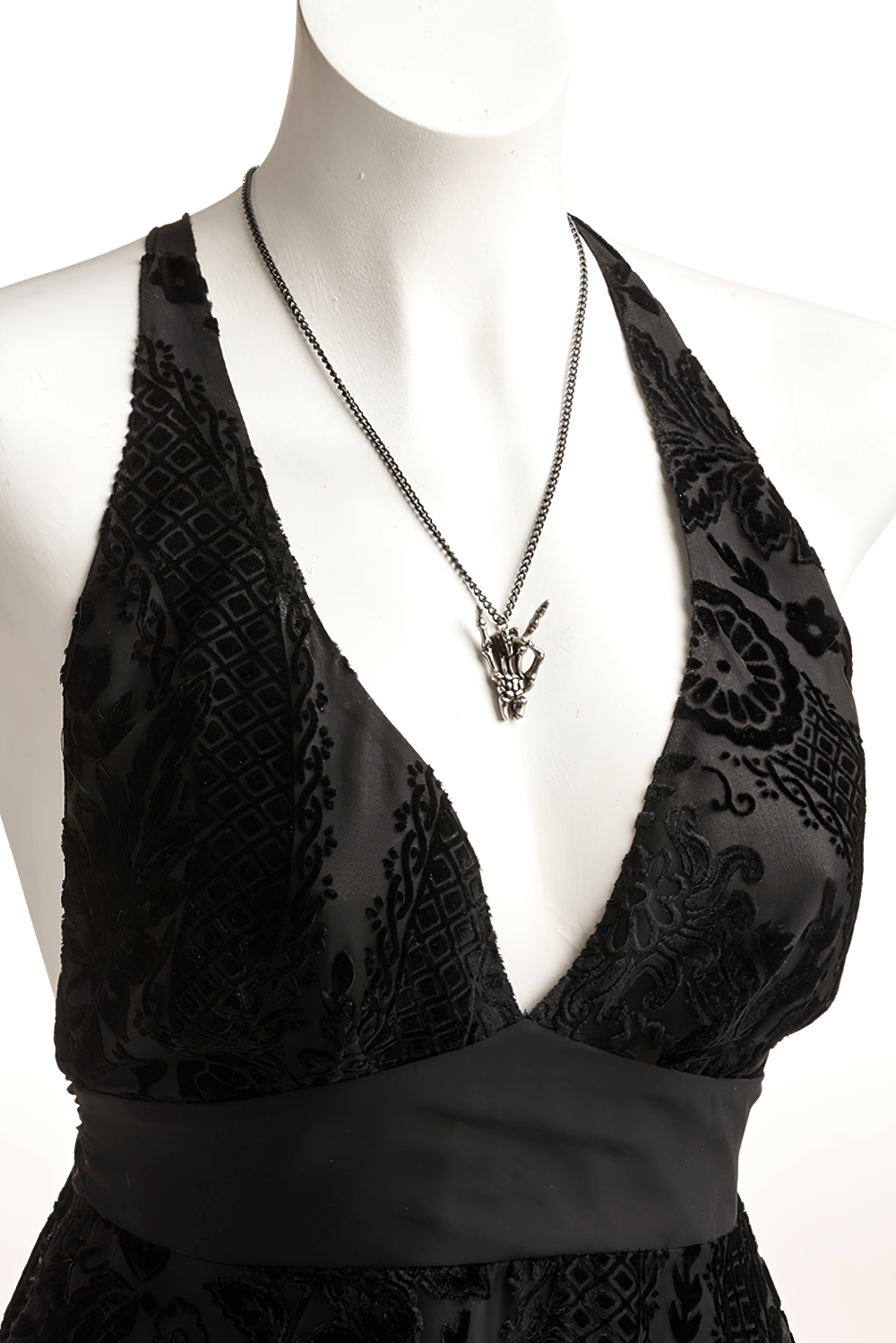 Black velvet dress featuring a Maloik skeletal hand pendant necklace for a stylish, mystical touch.