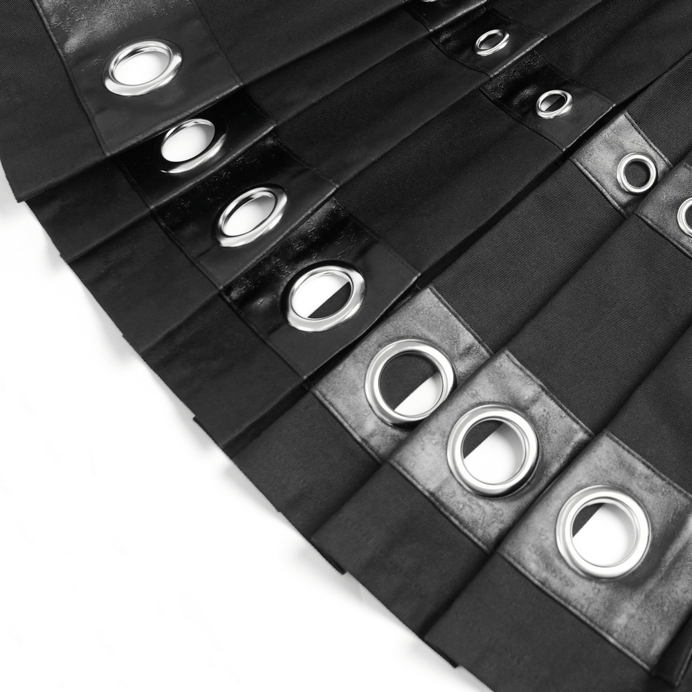 Close-up of black maxi skirt featuring shiny grommet details and pentagram straps for a stylish look.
