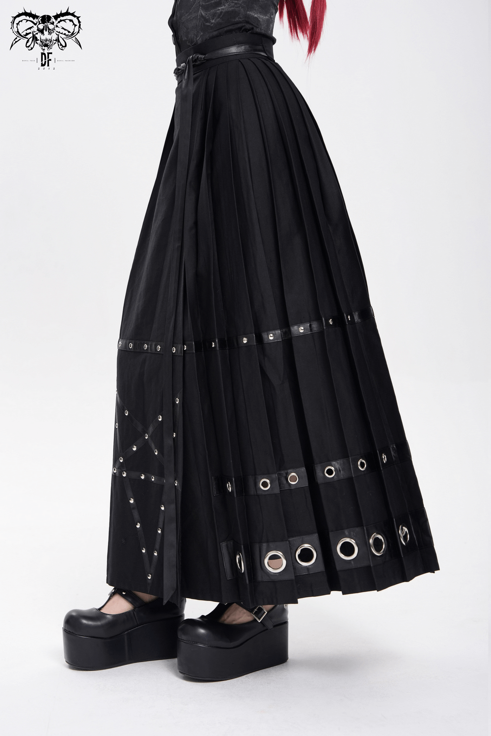 Elegant maxi skirt with pentagram straps and grommet details, styled with chunky platform shoes.