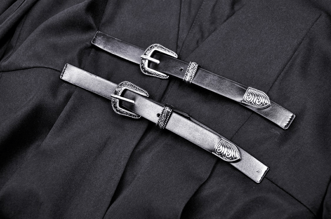 Close-up of decorative buckles on a black hooded cape, perfect for cosplay or Halloween costumes.