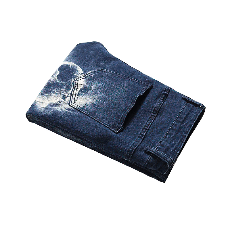 Folded men's blue 3D printed jeans with skull print, stylish streetwear denim pants for modern looks.